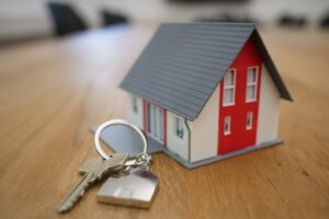 small toy house figurine with house key and keychain on wooden table