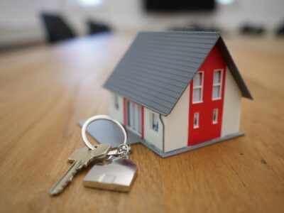 small toy house figurine with house key and keychain on wooden table