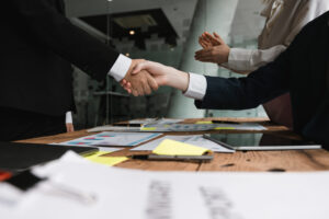 attorneys shaking hands over board room table paper deal