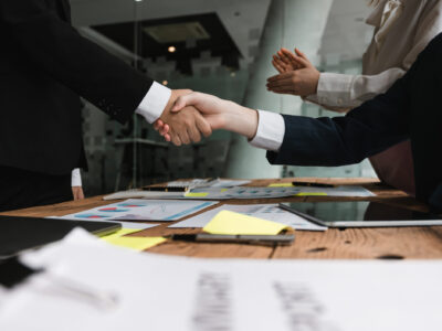 attorneys shaking hands over board room table paper deal