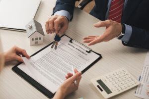 people reach over desk clipboard with rental agreement holding keys