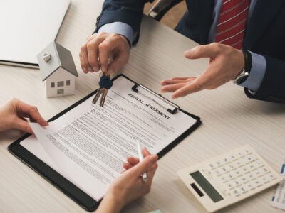 people reach over desk clipboard with rental agreement holding keys